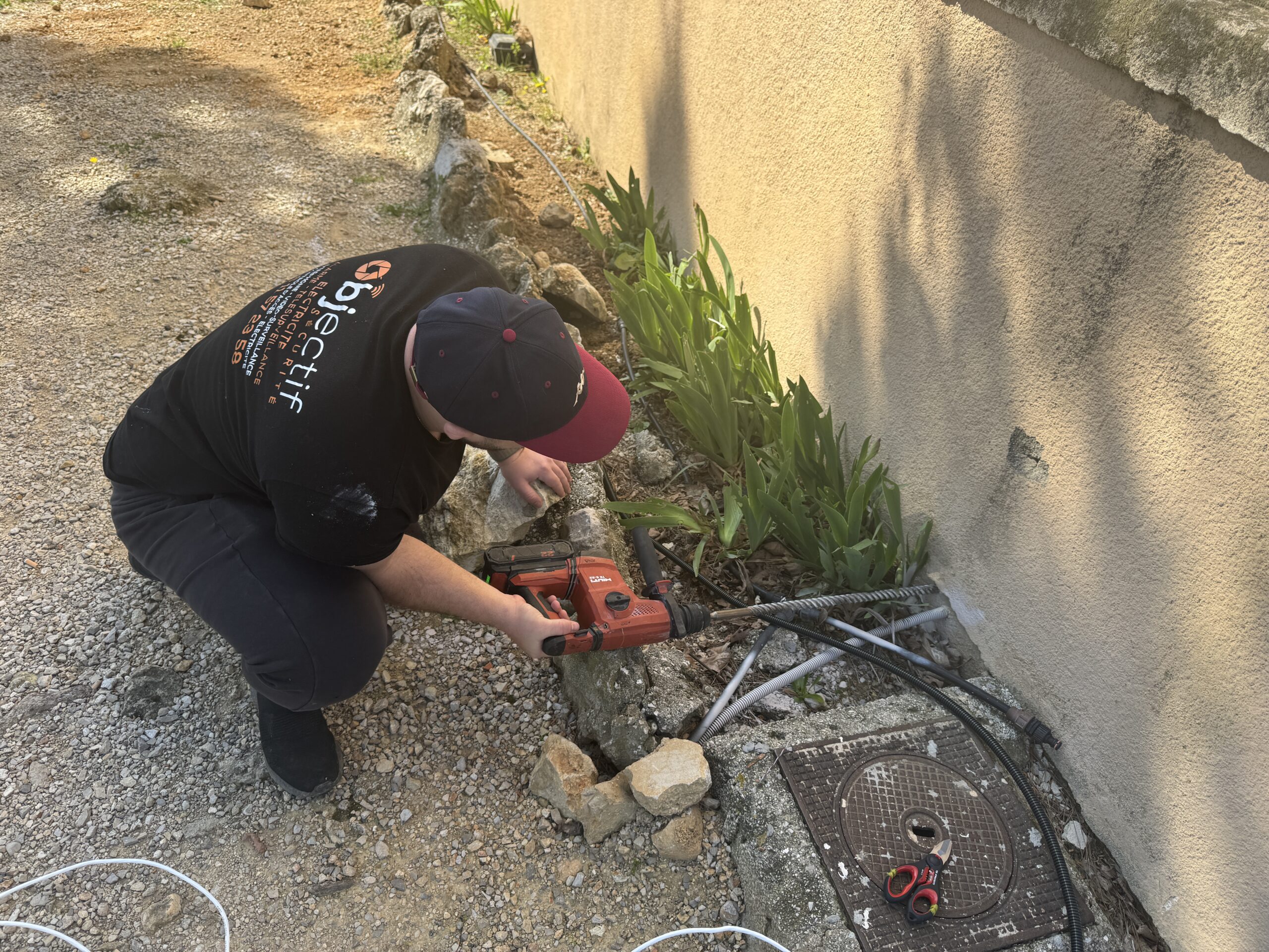 Résidence Saint Julien à Marseille, technicien intégrateur perforant le mur afin de faire passer le câble rejoignant le switch 50 mètres plus loin. Objectif Sécurité.