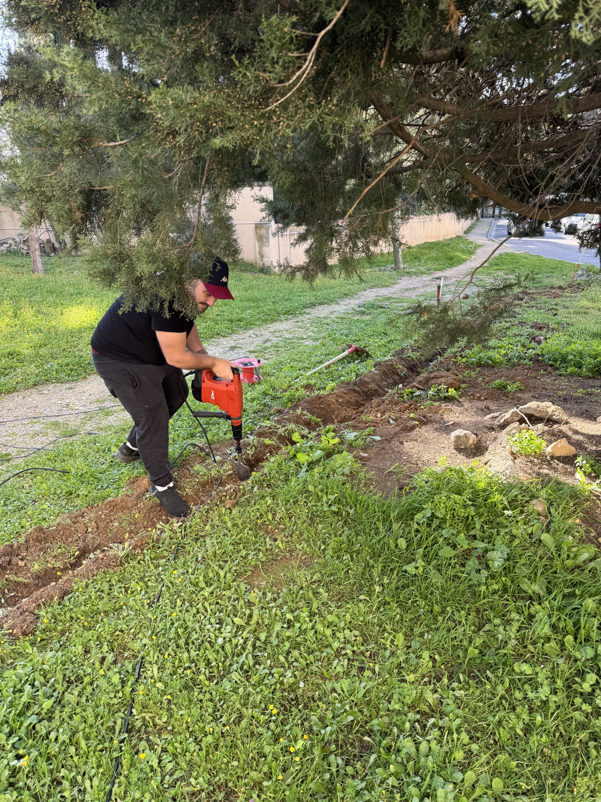 Résidence Saint Julien à Marseille, technicien intégrateur creusant une tranchée de 40 mètres pour installé la caméra 8K Dahua sur un arbre. Objectif Sécurité.